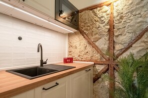 Eine Küche mit Holzarbeitsplatte, einem schwarzen Spülbecken und einer Steinwand.