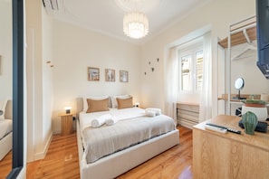 Ein Schlafzimmer mit einem Bett, Nachttischen, einem Schreibtisch, einem Spiegel und Bildern an der Wand.