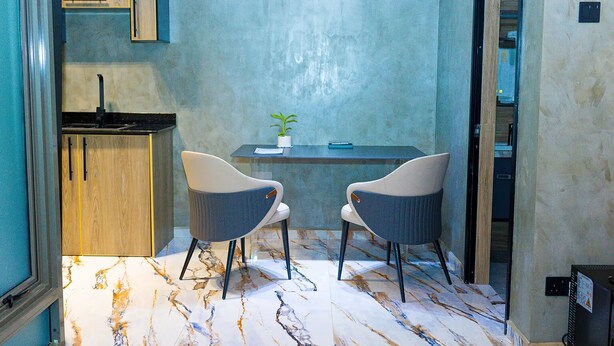 Cocina compacta con estufa integrada, una pequeña mesa de comedor con dos sillas y una planta en maceta sobre la mesa.