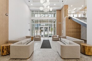 Eine moderne Lobby mit einer zentralen Sitzecke, Glastüren und einer Treppe.