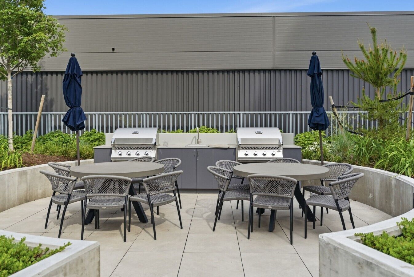Una terrazza esterna con barbecue, sedie e ombrelloni.