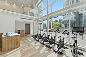 Ein Fitnessraum mit Ergometer, einer Rezeption und großen Fenstern.