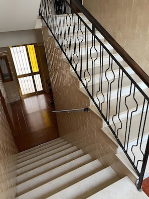 Eine Treppe mit schwarzem Metallgeländer, beige Wänden und einem gefliesten Boden.
