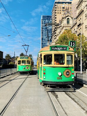 Eine Straßenbahn fährt auf Gleisen, im Hintergrund ein Gebäude.