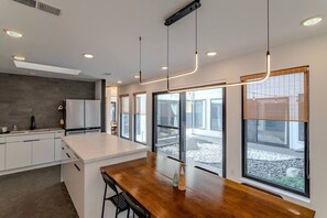 A modern kitchen with a central island, large windows, and a view of the outdoors. - Charming Houston Getaway (Houston)