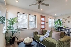 A living room with a sofa, a coffee table with a bowl of flowers, and a ceiling fan. - Cozy 3BR Richmond perfect for relaxation (Richmond)