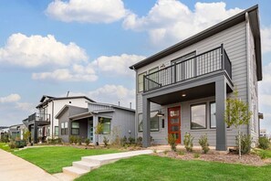 A row of modern two-story houses with balconies, a well-maintained lawn, and a clear sky. - Cozy 3BR Richmond perfect for relaxation (Richmond)