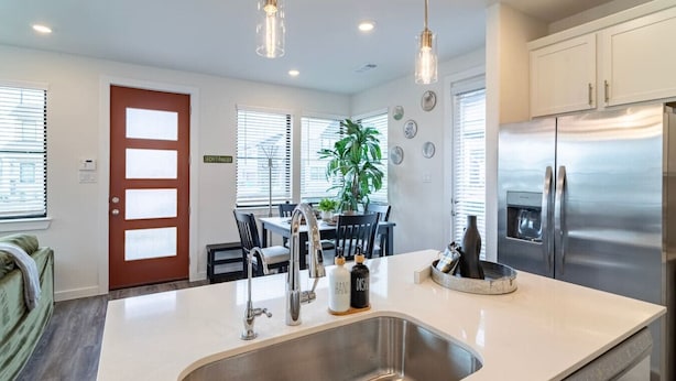 A modern kitchen with a stainless steel refrigerator, a built-in sink, and pendant lighting. - Cozy 3BR Richmond perfect for relaxation (Richmond)