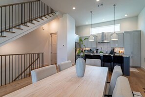 Eine moderne Küche mit Essbereich, Treppe und Pendelleuchten.