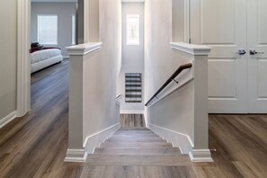 A staircase with a handrail, leading to a landing with a window. - Modern Maroon 3BR Home near Houston Downtown (Houston)