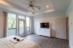 Ein Schlafzimmer mit einem Bett, einem Fernseher auf einer Kommode und einem Deckenventilator.