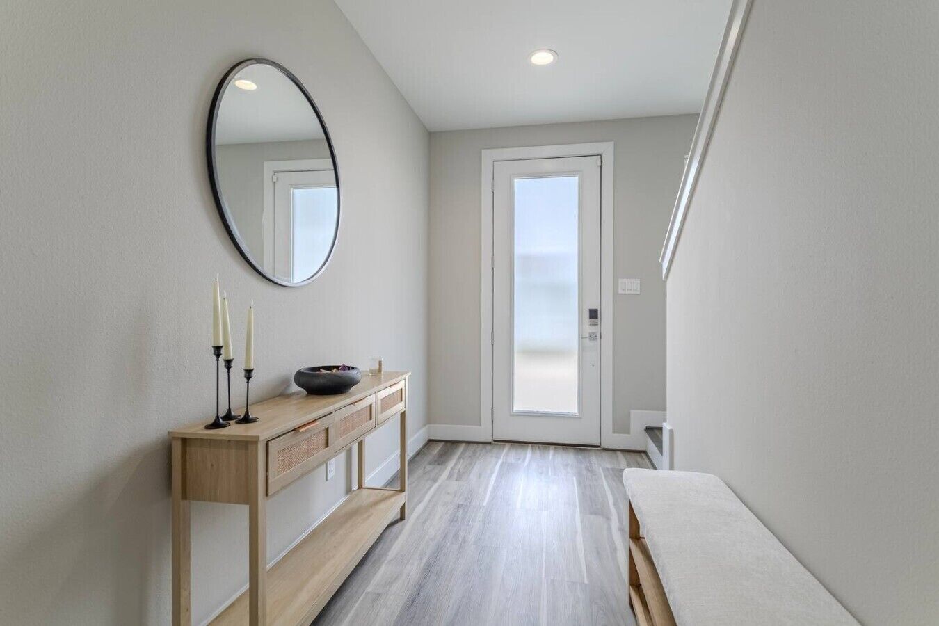 Een moderne hal met een houten console tafel, een spiegel en een deur die uitkomt op een balkon.