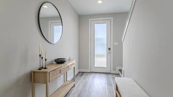 Een moderne hal met een houten console tafel, een spiegel en een deur die uitkomt op een balkon.