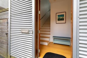 A room with a wooden floor, a bench, a staircase, and a painting on the wall. - Home for 4 near i10 / Memorial / Bayou Trails (Houston)