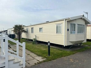 A mobile home with a front porch, a small garden area, and a white fence. - Lyons Robin Hood - Holiday Accommodation 17224 (Rhyl)