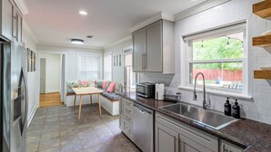 Una cocina moderna con comedor, muebles blancos, horno empotrado y ventana con vistas.