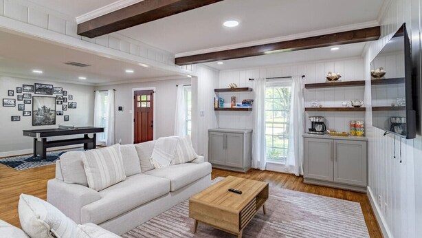 Una sala de estar moderna con sofá, mesa de centro y área de cocina con armarios y televisor.