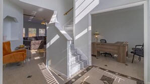 Un interior moderno con una escalera, un escritorio de madera y una zona de estar.