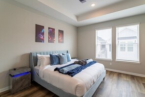 Ein Schlafzimmer mit einem Bett, einem Nachttisch und zwei Fenstern.