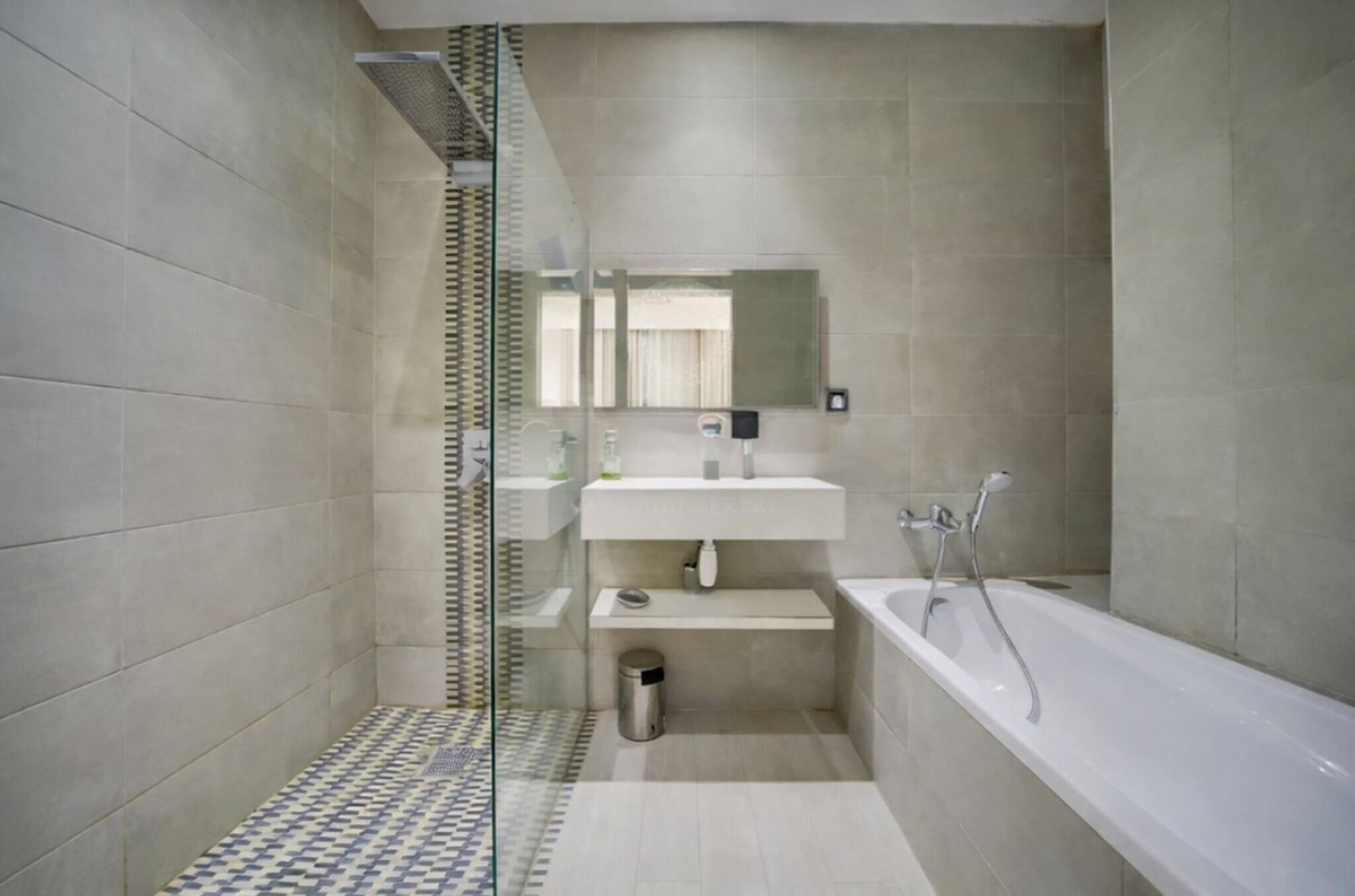 Un baño moderno con cabina de ducha de vidrio, un lavamanos blanco, un espejo y una bañera.