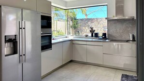 Eine moderne Küche mit Edelstahlgeräten, einer Steinrückwand und einem Fenster mit Blick auf Grünflächen.