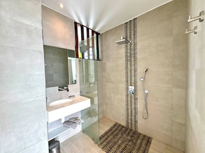 Un baño moderno con cabina de ducha de vidrio, un lavabo y un perchero para toallas.