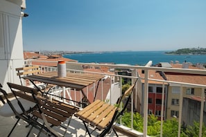 Ein Balkon mit Holzmöbeln, einem Metallstuhl und einem Blumentopf.
