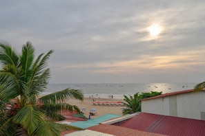 Vista de una playa con palmeras, piscina y un edificio de techo rojo.