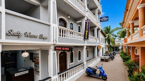 Un hotel con balcón, un cartel que dice 'Hotel Salty Waves Baga' y una pantalla digital que indica 'ROOMS @1999'.