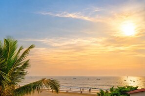 Une scène de plage avec des palmiers, un ciel dégagé et des bateaux sur l’eau.