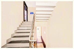 A staircase with a handrail, a sign on the wall, and a door at the top. - Hotel The Moon Light Inn Bhubaneswar (Bhubaneshwar)