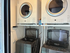 A laundry area with two front-loading washing machines and two dryers, with control panels and instruction manuals visible.