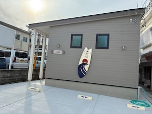 Een gebouw met een bord waarop staat dat het een hotel is, een surfboard decoratie en een parkeerplaats met een bord.