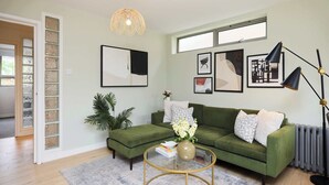 Ein Wohnzimmer mit einem grünen Sofa, einem runden Couchtisch und einem großen Fenster.