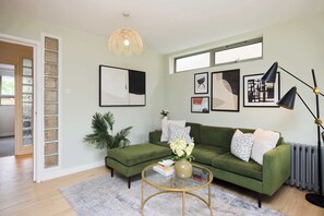 Ein Wohnzimmer mit einem grünen Sofa, einem runden Couchtisch und einem großen Fenster.