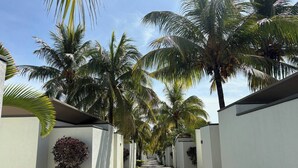 A pathway lined with white walls and palm trees, leading to a building with a flat roof. - Tropical Villa Athena Residence (Grand-Baie)