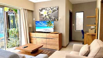 Una sala moderna con un televisor de pantalla plana, una mesa de centro de madera y un sofá.