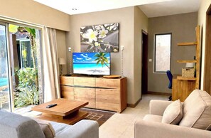 Ein modernes Wohnzimmer mit Flachbildfernseher, Couch und Couchtisch aus Holz.