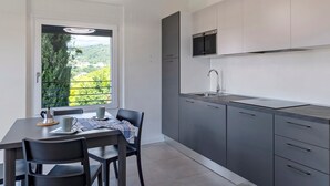 Une cuisine moderne avec des meubles gris, un évier en acier inoxydable et une fenêtre donnant sur un espace verdoyant.
