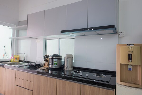 A modern kitchen with a black countertop, stainless steel appliances, and wooden cabinets.