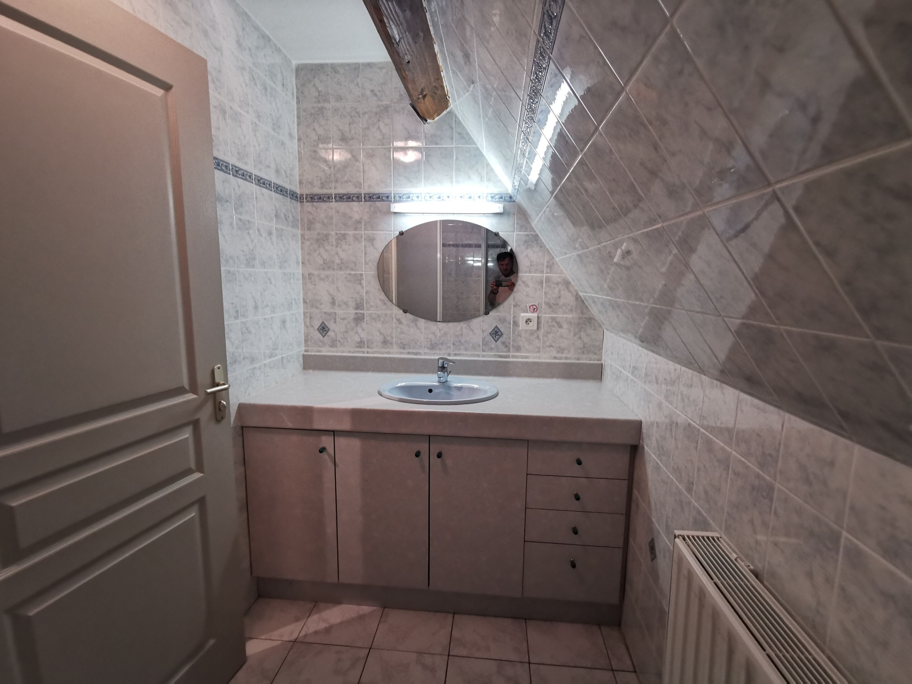 Une salle de bain avec un lavabo, un miroir et des murs carrelés.