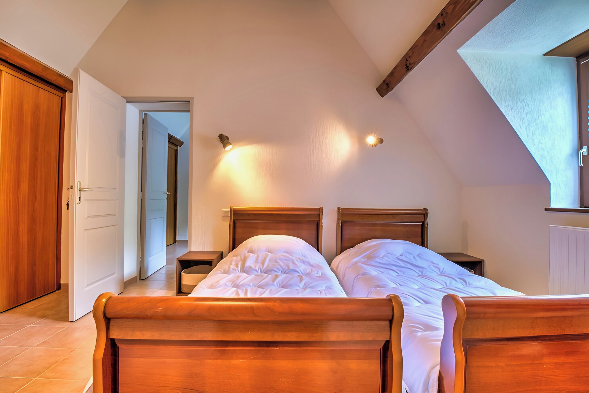 Camera da letto con un letto di legno, due comodini e un soffitto spiovente con travi a vista.