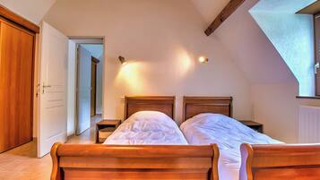 Camera da letto con un letto di legno, due comodini e un soffitto spiovente con travi a vista.