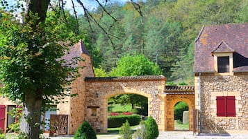 Un bâtiment en pierre doté d’une arche en pierre, d’une porte rouge et d’un jardin bien entretenu.