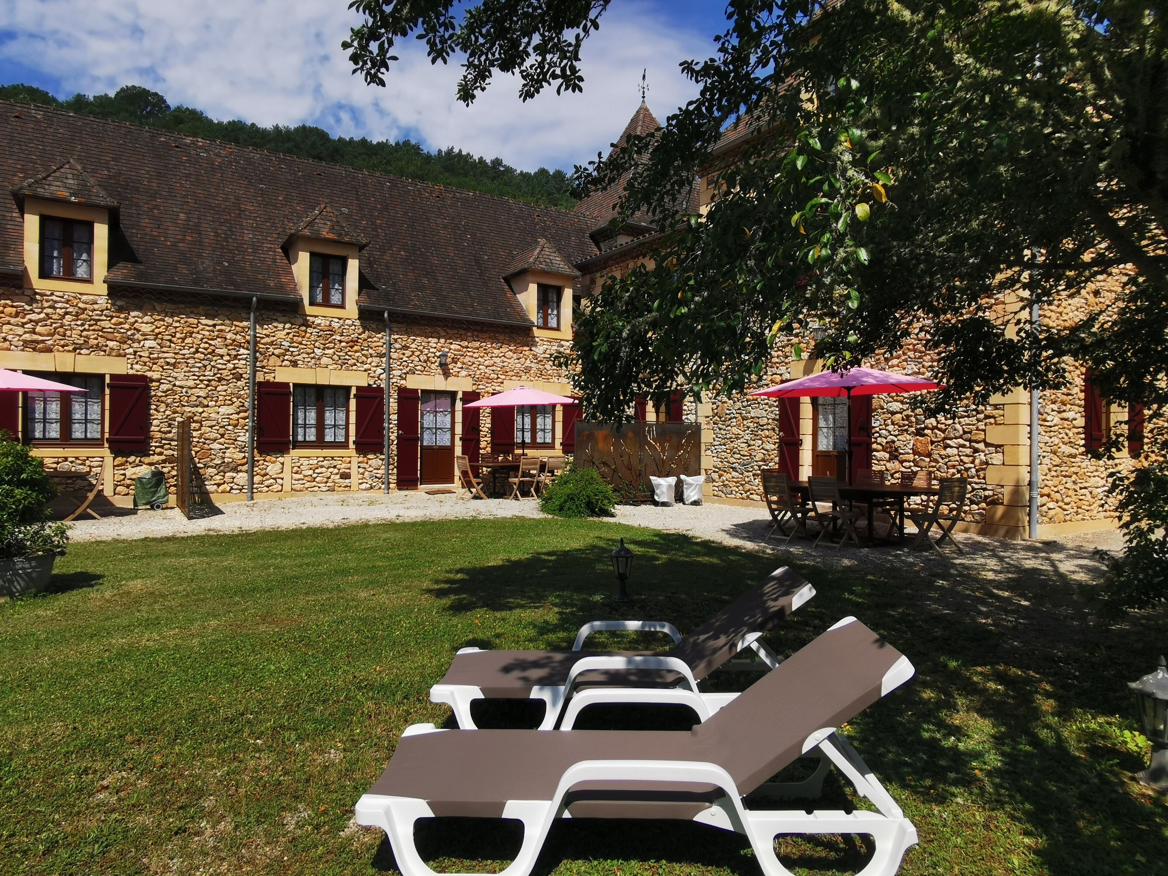 Un bâtiment en pierre doté d’une cour, d’un espace extérieur aménagé avec des sièges et de fauteuils confortables.