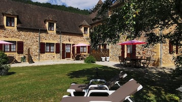 Un bâtiment en pierre doté d’une cour, d’un espace extérieur aménagé avec des sièges et de fauteuils confortables.