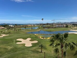 Ein Golfplatz mit Sandbunkern, Wasserhindernissen und Palmen.