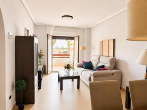 Ein modernes Wohnzimmer mit einer Couch, einem Couchtisch und Sesseln, ein Essbereich mit Tisch und Stühlen sowie ein Blick ins Freie.