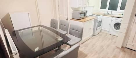 A compact kitchen with a dining area, a washing machine, and a small window.