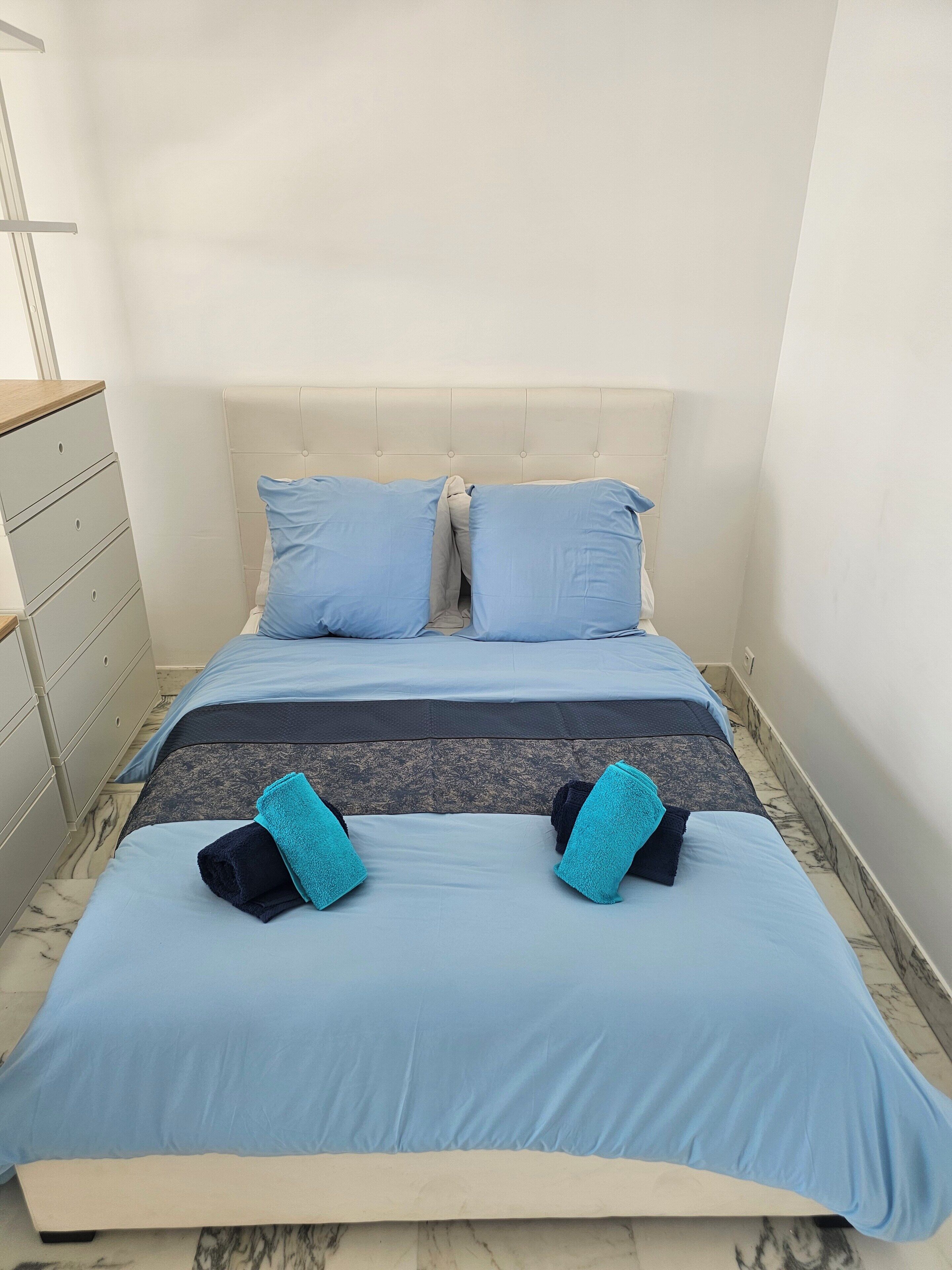 Un lit avec une tête de lit, une commode et un sol en marbre.